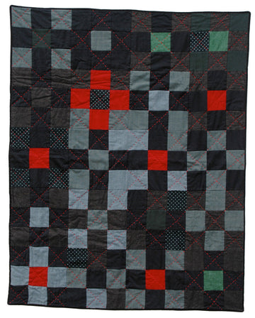 traditional 9 patch quilt hand stitched with red tread. the fabric is. mostly gray and black and a few abstract pops of red, green and polka dot fabric